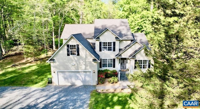 view of front facade featuring a front lawn, driveway, a forest view, and an attached garage