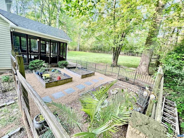 exterior space featuring fence, a vegetable garden, and a sunroom