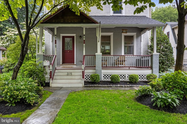 315 Vassar Ave, Swarthmore, PA 19081 - view of front of home with stucco siding, covered porch, a front lawn, and roof with shingles