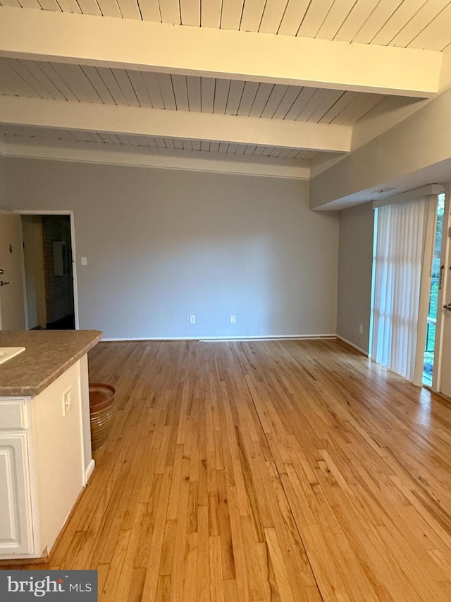 interior space with light wood finished floors, baseboards, beam ceiling, and wood ceiling