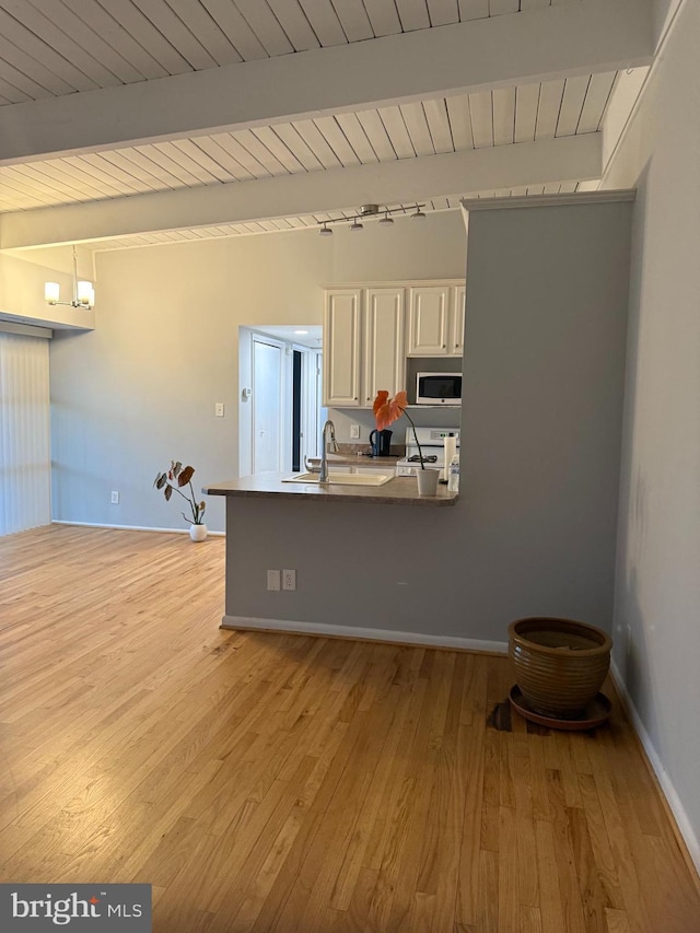 kitchen with wooden ceiling, stainless steel microwave, beamed ceiling, light wood finished floors, and white gas stove