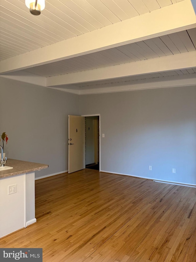 spare room with beam ceiling, light wood-style floors, wood ceiling, and a sink