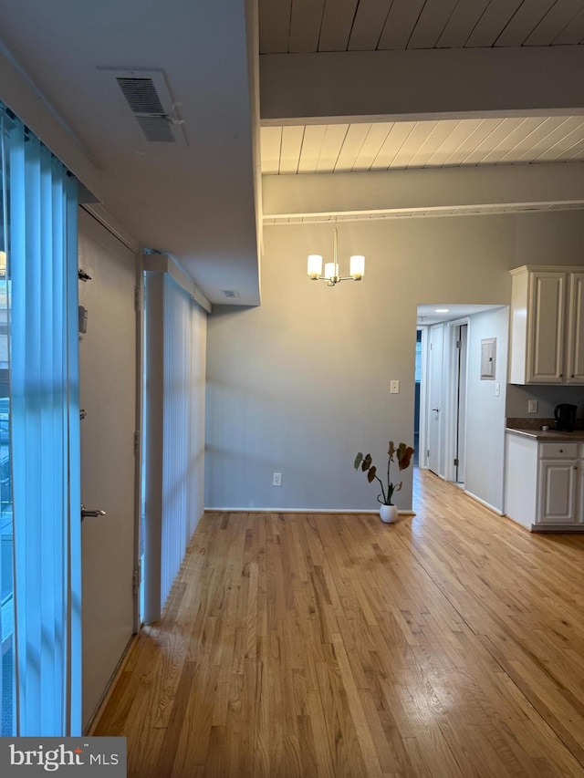 unfurnished dining area with beamed ceiling, an inviting chandelier, wooden ceiling, light wood-type flooring, and visible vents