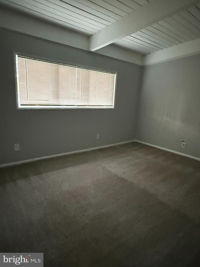 spare room with beam ceiling, carpet floors, and baseboards