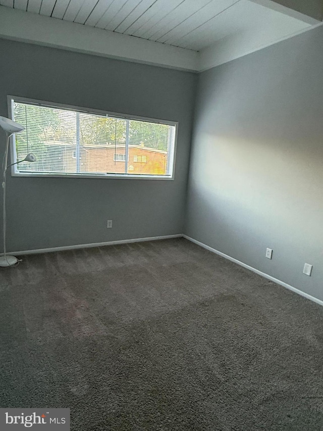 spare room with baseboards, beamed ceiling, carpet flooring, and wood ceiling