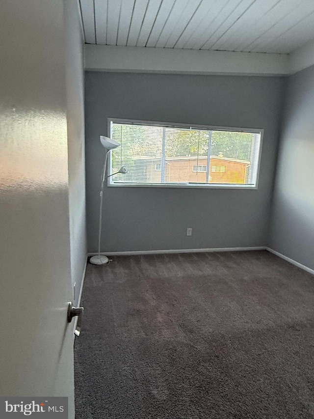 spare room featuring baseboards, carpet, and wood ceiling