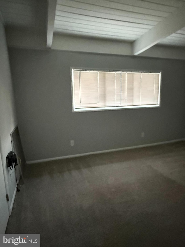 unfurnished room featuring baseboards, beamed ceiling, and carpet