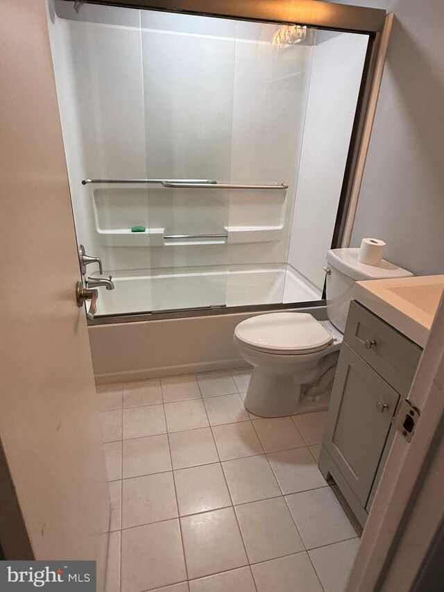 bathroom with toilet, tile patterned flooring, enclosed tub / shower combo, and vanity
