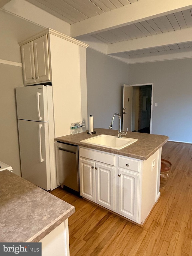 kitchen featuring beamed ceiling, a sink, freestanding refrigerator, dishwasher, and a peninsula