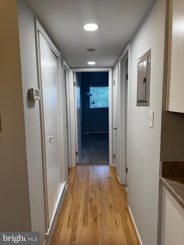 corridor featuring light wood-style floors, electric panel, and baseboards