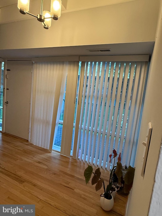interior space with visible vents, wood finished floors, and a notable chandelier