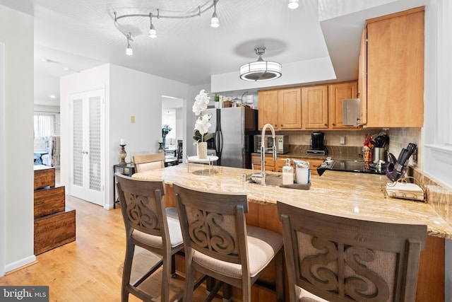 8101 Greenspring Way Unit 8101-E, Owings Mills, MD 21117 - kitchen featuring light stone counters, decorative backsplash, light wood-style floors, stainless steel fridge with ice dispenser, and a peninsula