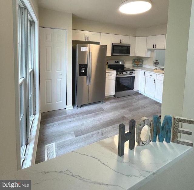 20002 Apperson Pl, Germantown, MD 20876 - kitchen with appliances with stainless steel finishes, light stone counters, white cabinetry, light wood-type flooring, and visible vents