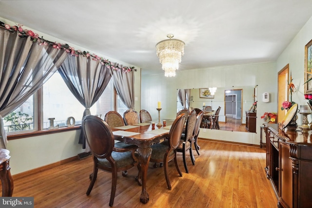 dining room featuring baseboards, light wood-style flooring, and a notable chandelier