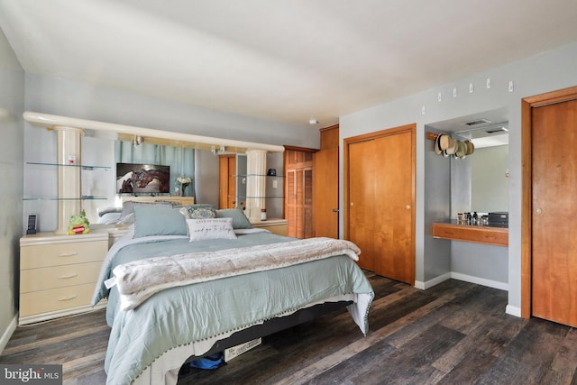bedroom featuring baseboards, wood finished floors, and two closets