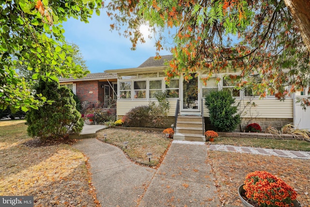 bungalow featuring a sunroom and brick siding