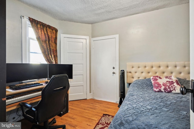 bedroom with light wood-type flooring and a textured ceiling