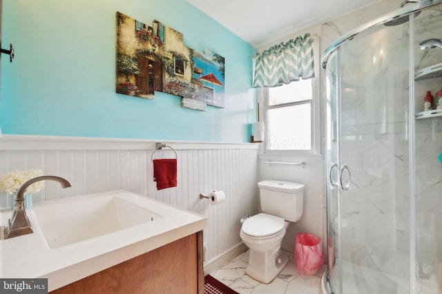 bathroom featuring vanity, a marble finish shower, a wainscoted wall, and toilet