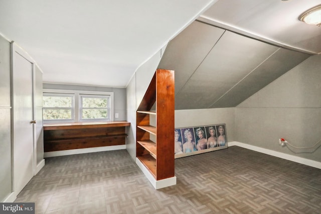 additional living space with baseboards and vaulted ceiling