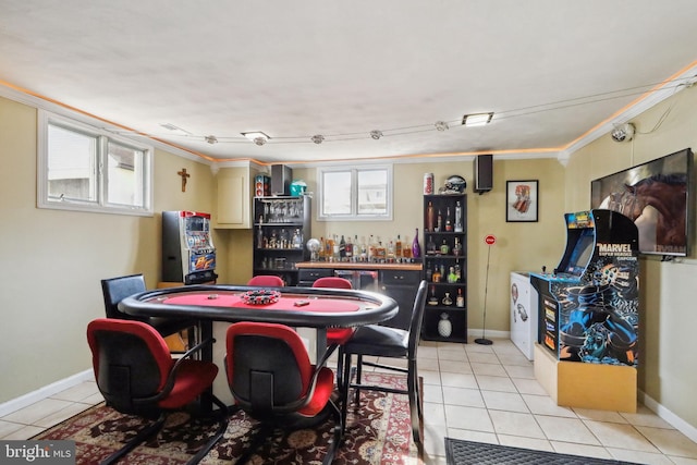 rec room featuring crown molding, light tile patterned flooring, baseboards, and a dry bar
