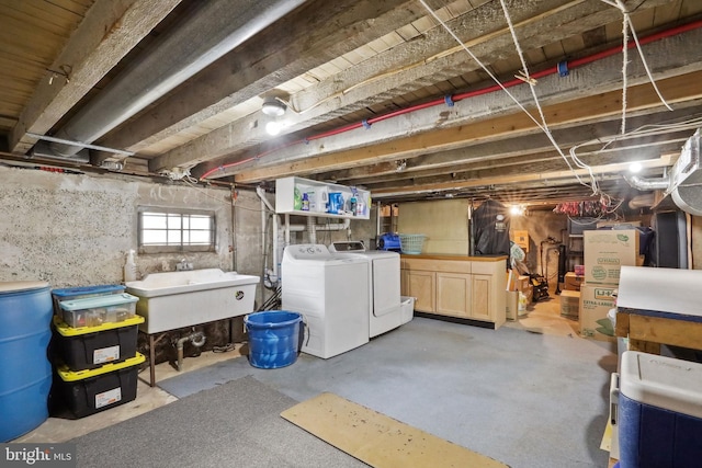 basement featuring independent washer and dryer, a sink, and water heater