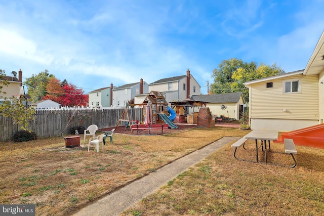 view of playground with a yard, a residential view, fence, and an outbuilding