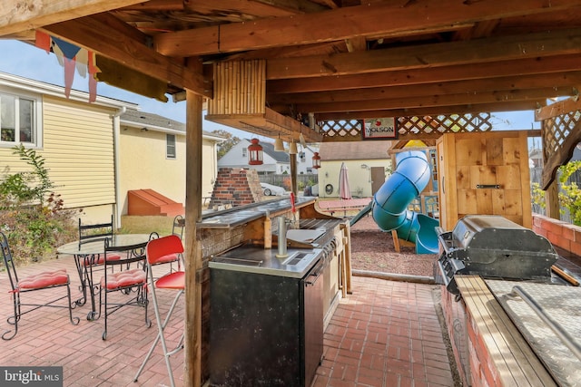 view of patio with a playground and an outdoor kitchen