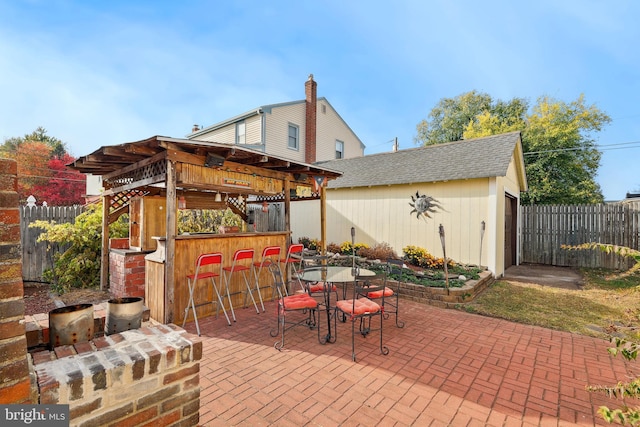 view of patio / terrace with a fenced backyard, outdoor dry bar, and an outbuilding