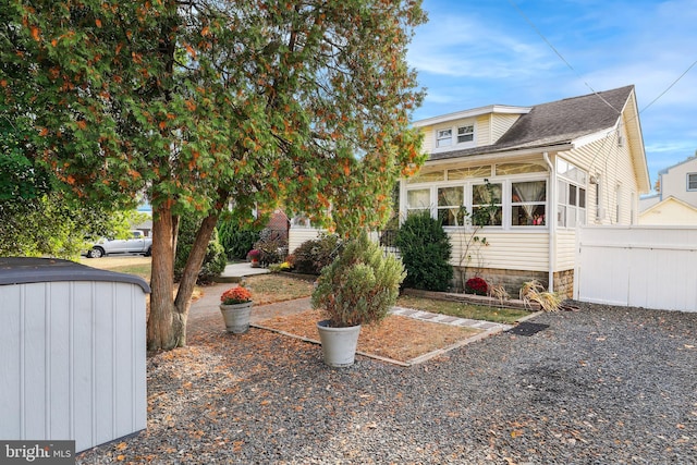 view of front of property with fence, an outbuilding, a sunroom, and a storage unit