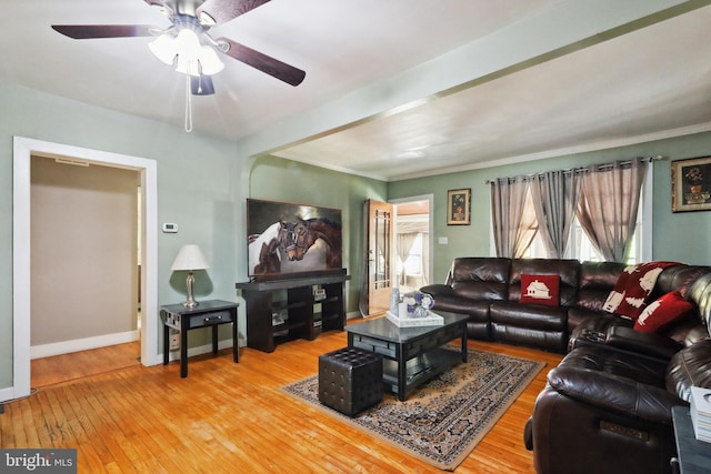 living area featuring wood-type flooring, a ceiling fan, and baseboards