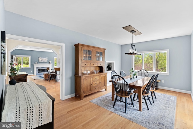 dining space featuring a premium fireplace, plenty of natural light, light wood finished floors, and baseboards