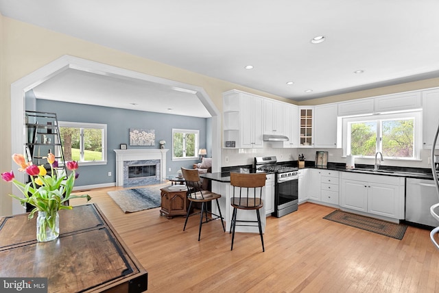 kitchen with dark countertops, stainless steel appliances, white cabinets, and a sink