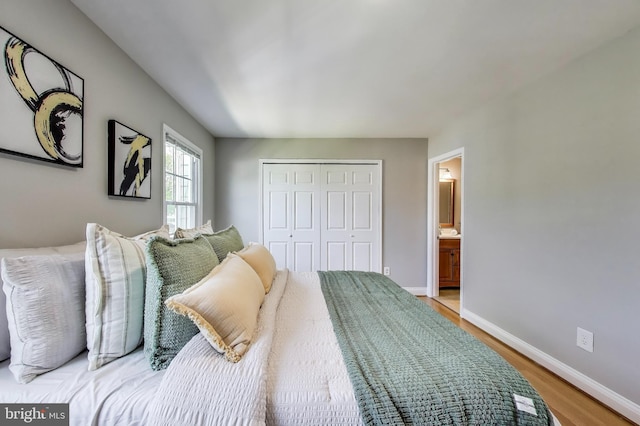 bedroom featuring connected bathroom, baseboards, light wood-style flooring, and a closet