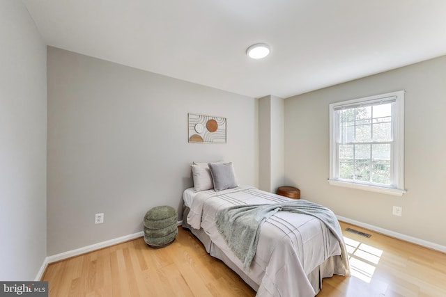 bedroom featuring baseboards, light wood-style flooring, and visible vents