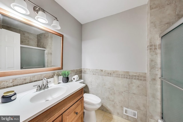 full bathroom featuring vanity, toilet, tile walls, visible vents, and a stall shower