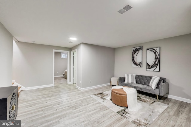 living area featuring baseboards, light wood finished floors, and visible vents