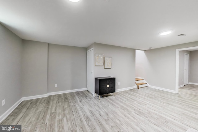finished below grade area with light wood-style floors, baseboards, and visible vents