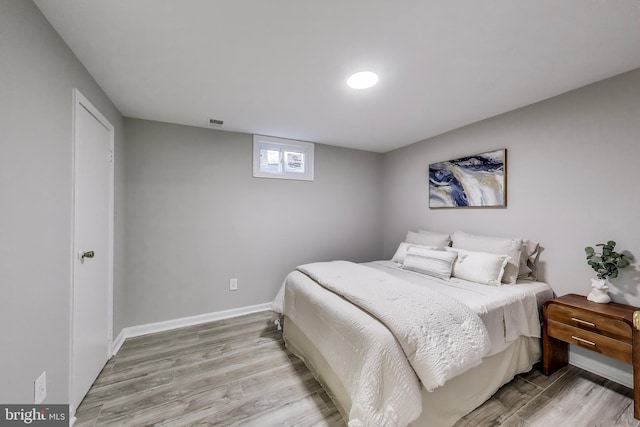 bedroom with baseboards, light wood finished floors, and visible vents