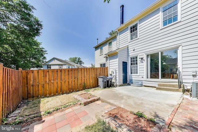 rear view of house featuring a patio, a fenced backyard, and central AC