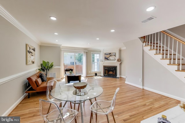 dining space featuring crown molding, recessed lighting, light wood-type flooring, and a fireplace with flush hearth