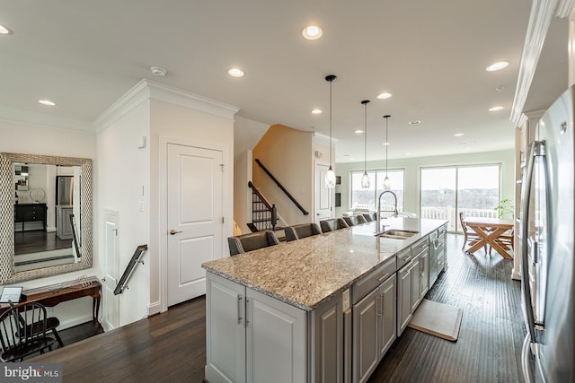 kitchen featuring recessed lighting, gray cabinets, a kitchen island with sink, freestanding refrigerator, and a sink