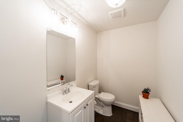 bathroom featuring vanity, toilet, visible vents, baseboards, and wood finished floors