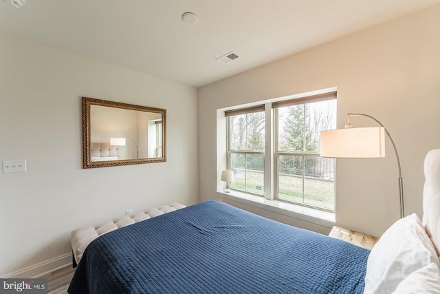 bedroom featuring baseboards, visible vents, and wood finished floors