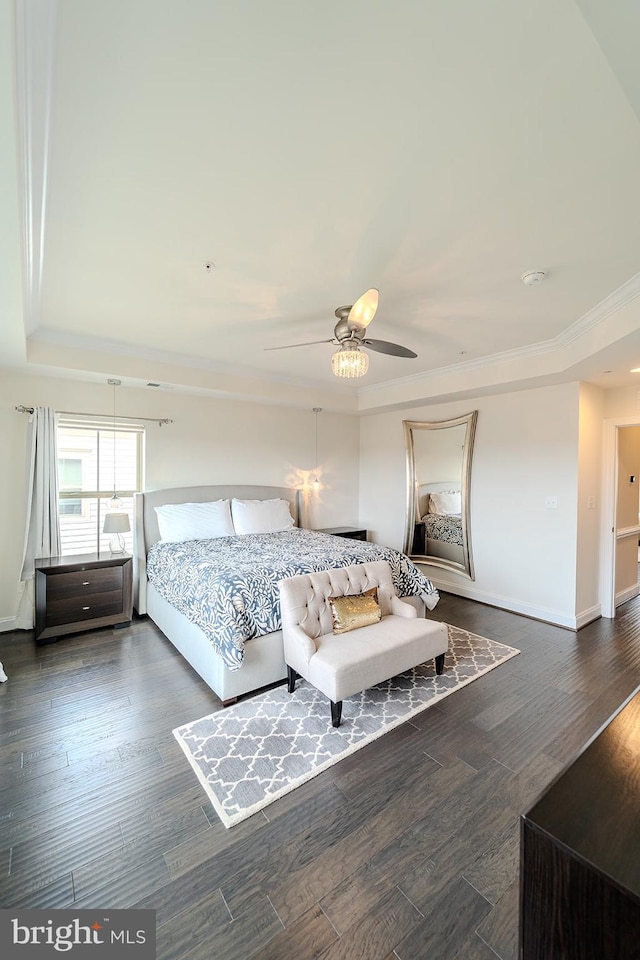 bedroom with crown molding, ceiling fan, a raised ceiling, baseboards, and dark wood-type flooring