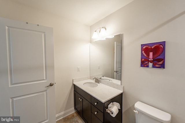 half bathroom with toilet, vanity, and baseboards