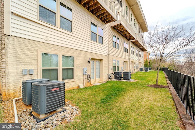 rear view of house with fence, central AC, a yard, and brick siding