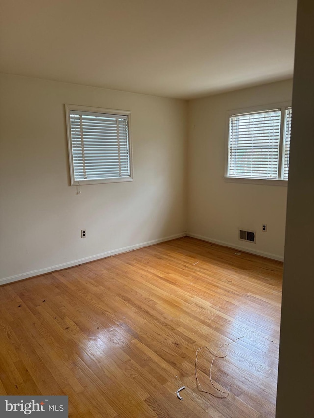 empty room featuring baseboards, visible vents, and light wood-style floors