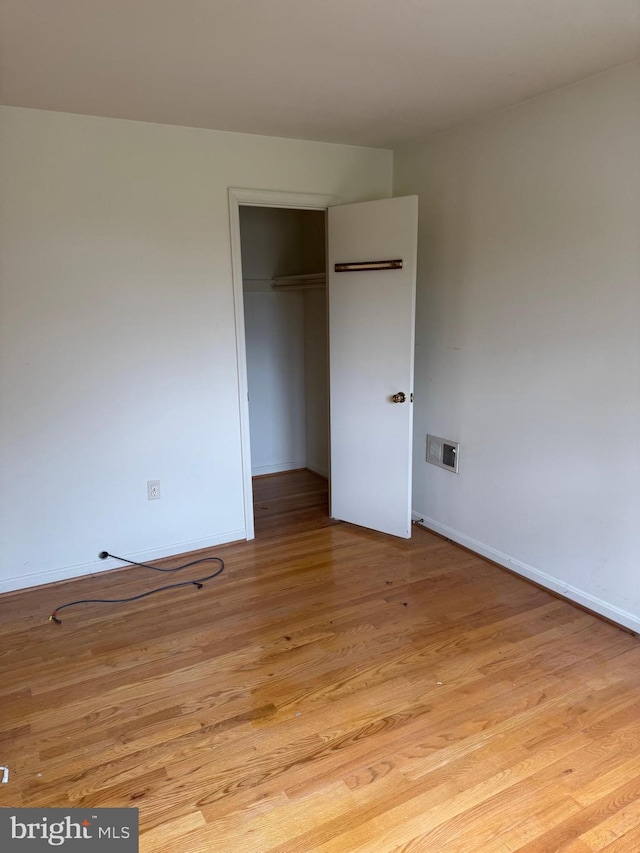 unfurnished bedroom featuring baseboards, light wood-style flooring, and a closet