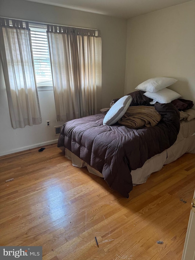 bedroom featuring wood finished floors, visible vents, and baseboards