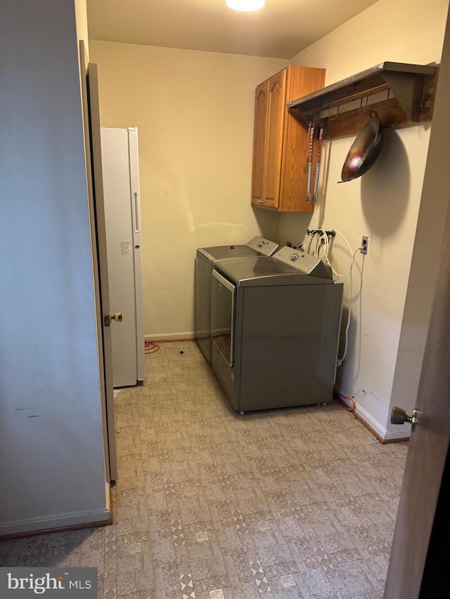 laundry room with baseboards, separate washer and dryer, and cabinet space